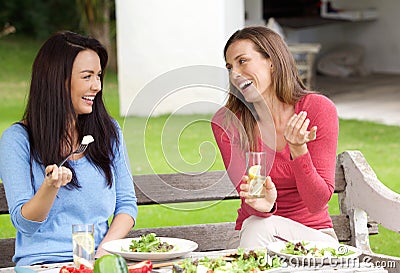 Two women friends sitting outside in garden having lunch Stock Photo