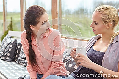 Two women friends talking holding coffee cups Stock Photo