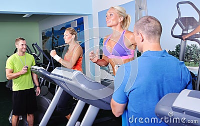 Two women in gym exercising with personal fitness trainer Stock Photo