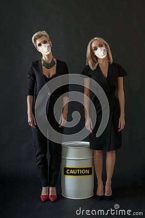 Two women in medical mask and black suit posing on black background. Toxic pollution, global pandemic and environmental protection Stock Photo