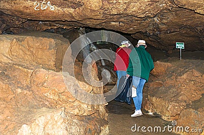 Two women, members of the tourist group, pose against the backdrop of the cave. Red Cave Stock Photo