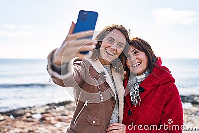 Two women mother and daughter make selfie by smartphone at seaside Stock Photo