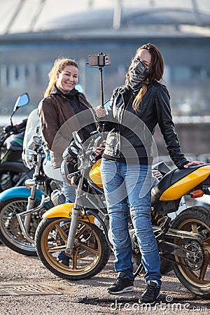 Two women motorcyclists making photo with selfie stick and front camera of cellular Stock Photo