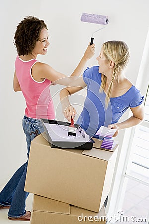 Two women painting room in new home smiling Stock Photo