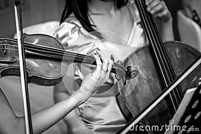 Two women playing violin and cello in a chamber orchestra shot in black and white Stock Photo