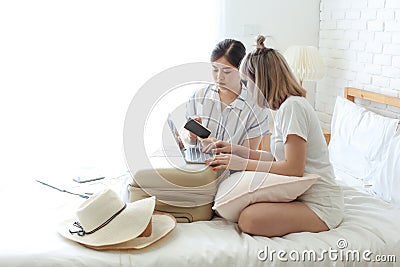 Two women are preparing to travel. Sisters and sisters are checking ticket and hotel reservations for tourism Stock Photo