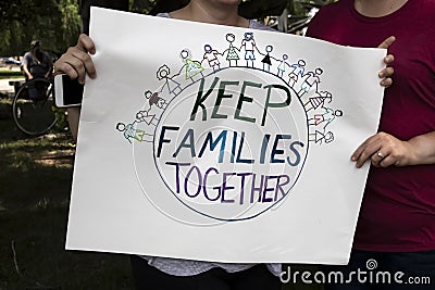 Two women at protest holding homemade sign together that says keep families together with world and families holding hands on it Stock Photo