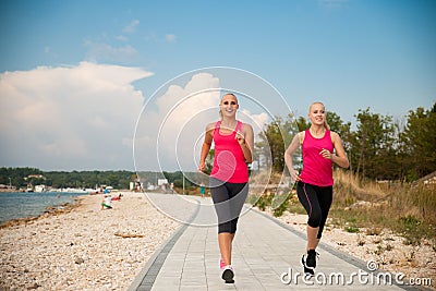 Two women athlets running on the beach - early morning summer w Stock Photo