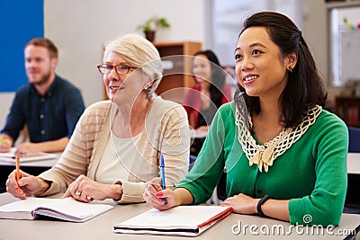 Two women sharing a desk at an adult education class look up Stock Photo