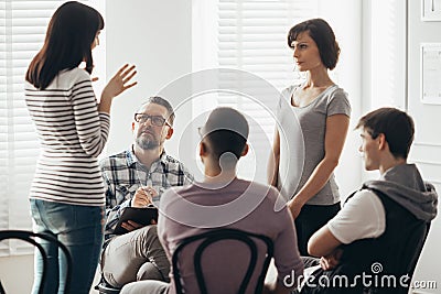Two women standing and talking during group therapy with psychologist Stock Photo