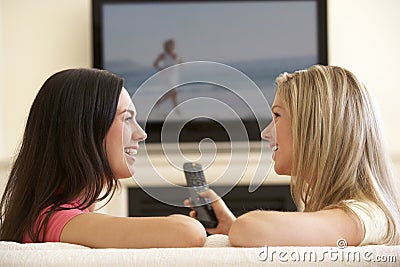 Two Women Watching Sad Movie On Widescreen TV At Home Stock Photo