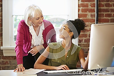 Two Women Working At Computer In Contemporary Office Stock Photo