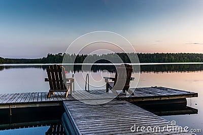 Two wooden chairs at Sunset on a pier on the shores of the calm Saimaa lakein Finland - 3 Stock Photo
