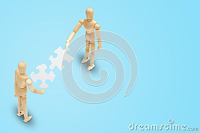 Two wooden figure mannequin holding and connecting white paper puzzle piece together. Stock Photo