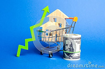 Two wooden houses in a trading cart and green arrow up and money bundle. Increasing cost and liquidity of real estate. Attractive Stock Photo