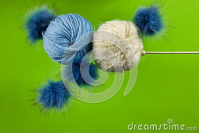 Two wool balls and fur pom poms on green Stock Photo