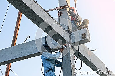 two worker man climbing high concrete pile for welding steel house structure in construction site Editorial Stock Photo