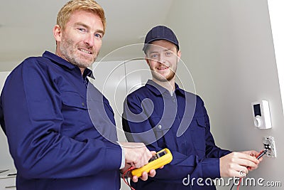 Two workers calibrating wall sockets Stock Photo