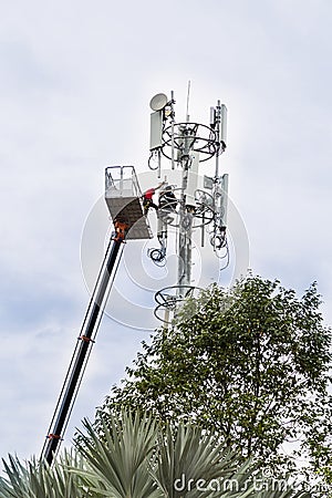 Two workers on crane installing mobile network communication ant Stock Photo