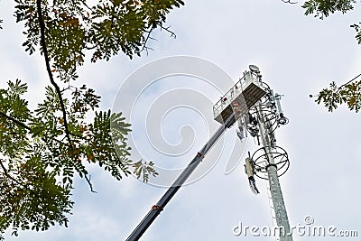 Two workers on crane installing mobile network communication ant Stock Photo