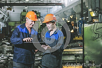 Two workers at an industrial plant with a tablet in hand, workin Stock Photo