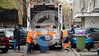 Two workers loading mixed domestic waste in waste collection truck from town Editorial Stock Photo