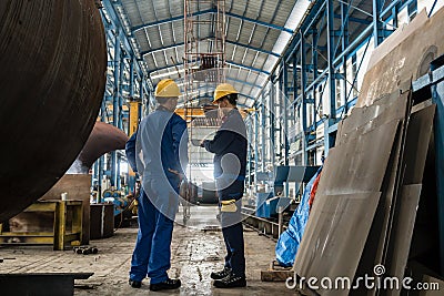 Two workers wearing yellow hard hat and blue uniform Stock Photo