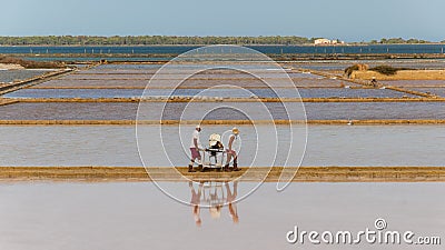 Two workers at the west coast salt pans in Marsala Editorial Stock Photo
