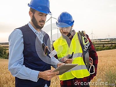 Two working men in a field of windmills. Renewable energies, engineers Stock Photo