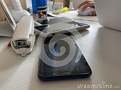 Two working touchscreen mobile phones, smartphones lie on the table in the office with stationery, a stapler, a seal and a laptop Stock Photo