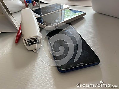 Two working touchscreen mobile phones, smartphones lie on the table in the office with stationery, a stapler, a seal and a laptop Stock Photo
