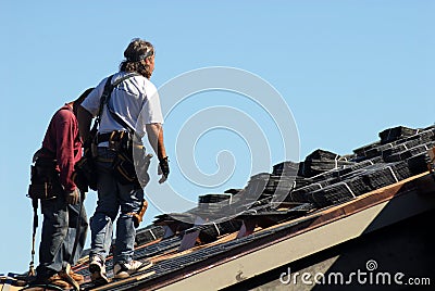 Two workmen walking on roof of building Stock Photo