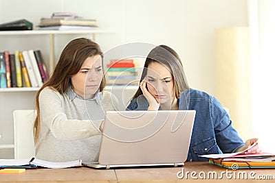 Two worried students consulting online information in a laptop Stock Photo