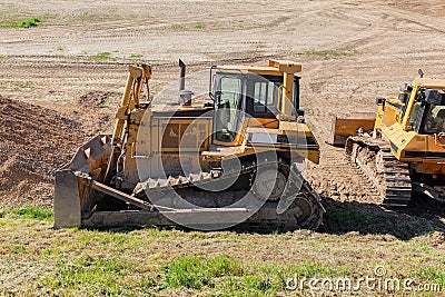 Two yellow dozers on a dirt terrain with blue sky Stock Photo