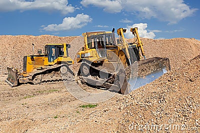 Two yellow dozers on a dirt terrain with blue sky Stock Photo