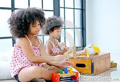 Two young African girls play toys together with main focus on front girl who look enjoy with her toys Stock Photo