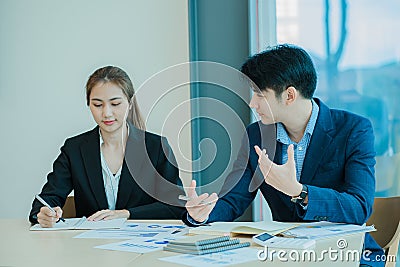 Two young Asian businessmen working together at the Financial Graph computer office. Share ideas, discuss and train business plans Stock Photo