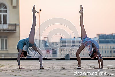 Two young ballerinas dancing in pointe shoes in city against the backdrop of sunset sky Stock Photo