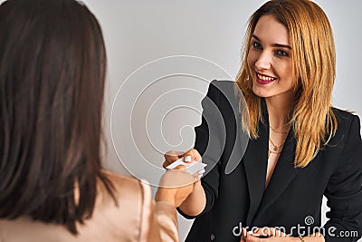 Two young beautiful businesswomen exchanging visit card Stock Photo