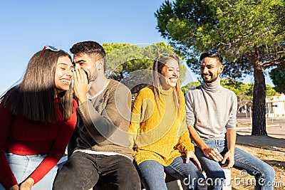 Two young beautiful heterosexual couple laughing each other. Happy millennial group of people having fun outdoor. Man speaks in Stock Photo