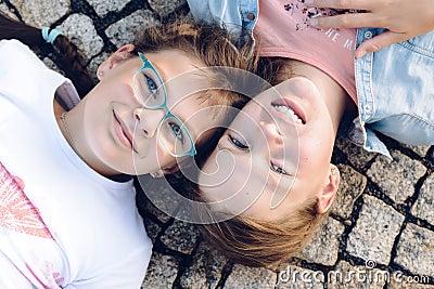 Two young blonde girls lying on the ground with eyes open and their heads side by side Stock Photo