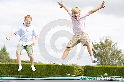 Two young boys jumping on trampoline smiling Stock Photo