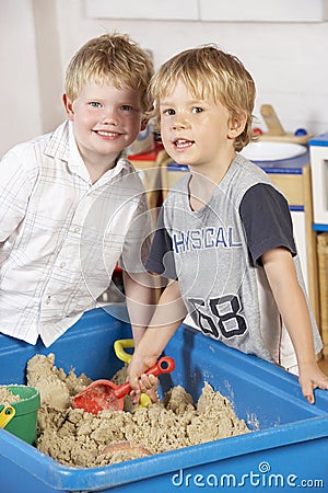 Two Young Boys Playing Together in Sandpit Stock Photo