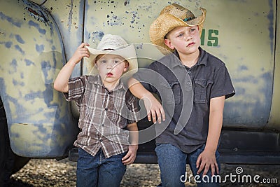 Two Young Boys Wearing Cowboy Hats Leaning Against Antique Truck Stock Photo