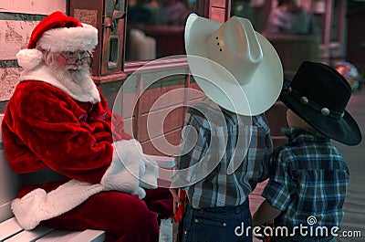 Two young buckaroo kids talk things over with Santa Editorial Stock Photo