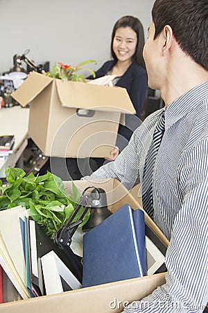 Two young business people carrying boxes with office items Stock Photo