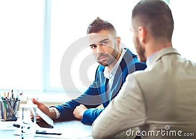 Two young businessmen using touchpad at meeting Stock Photo