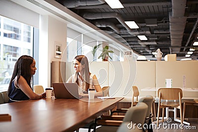 Two Young Businesswomen Having Informal Interview In Cafeteria Area At Graduate Recruitment Assessment Day Stock Photo