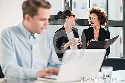 Two young cheerful female employees talking in the office Stock Photo