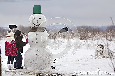 Two young children, boy and girl, finish doing smiling snowman i Stock Photo